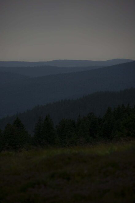 Donker fotografisch beeld waarop bergen en een blauwe horizon te zien zijn - natuurfotografie door Tamara De Prest