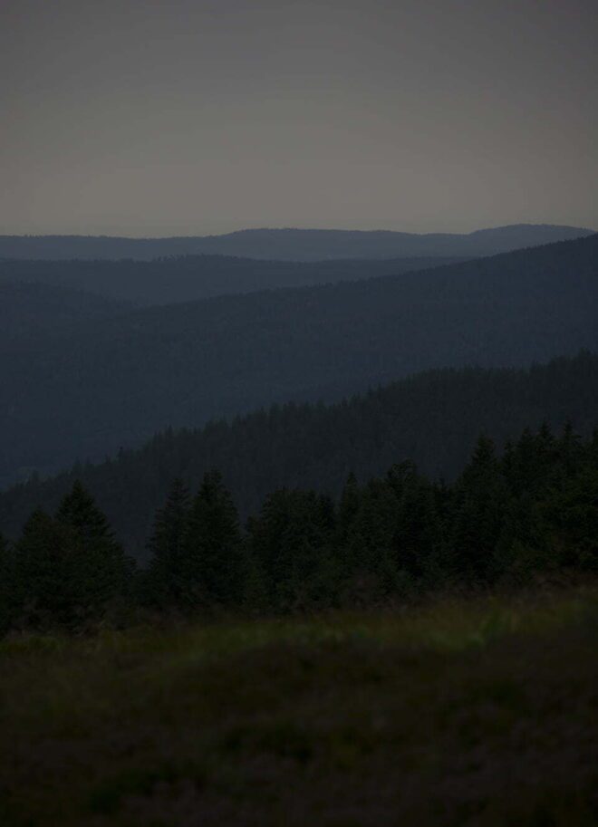 Donker fotografisch beeld waarop bergen en een blauwe horizon te zien zijn - natuurfotografie door Tamara De Prest